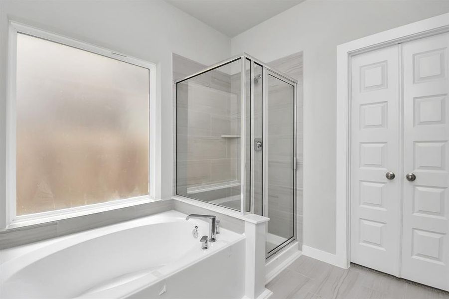 This additional view of the primary bath features a walk-in shower with the tile surround and separate garden tub perfect for soaking after a long day. Sample photo of completed home with similar floor plan. Actual colors and selections may vary.