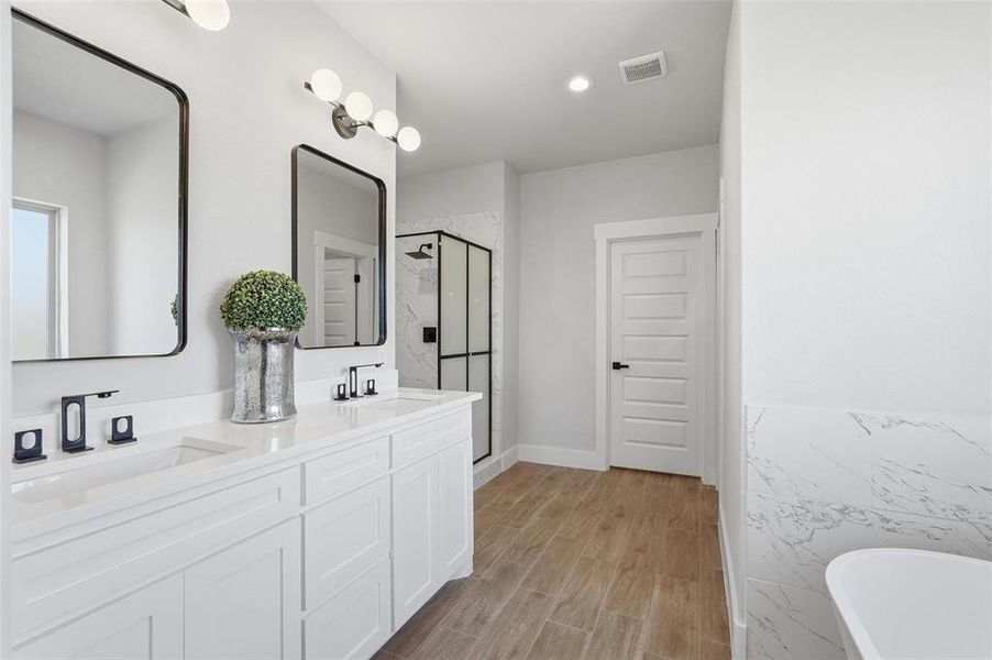 Full bathroom with a marble finish shower, double vanity, wood finish floors, a soaking tub, and recessed lighting