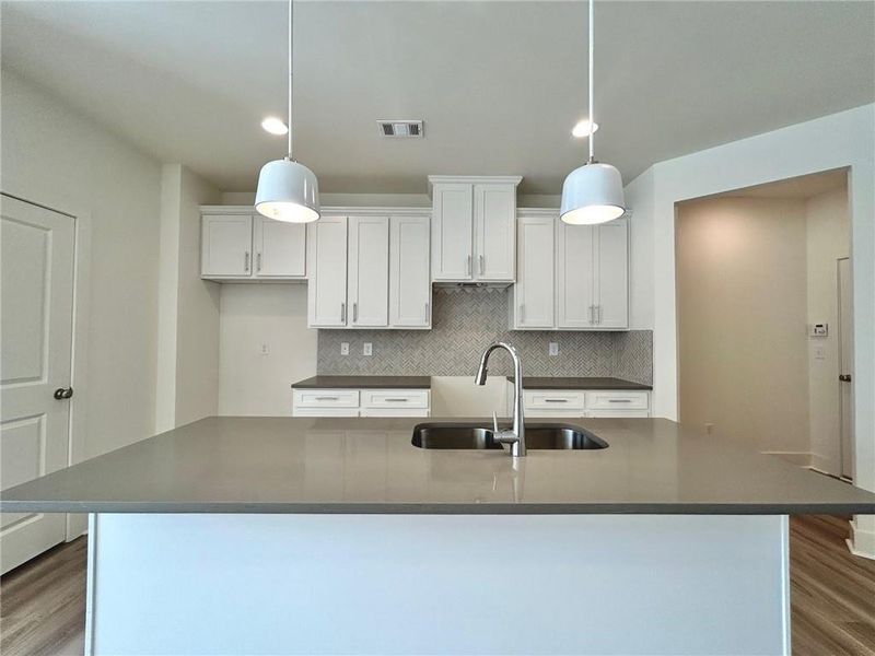 Kitchen featuring pendant lighting, sink, white cabinetry, and hardwood / wood-style flooring