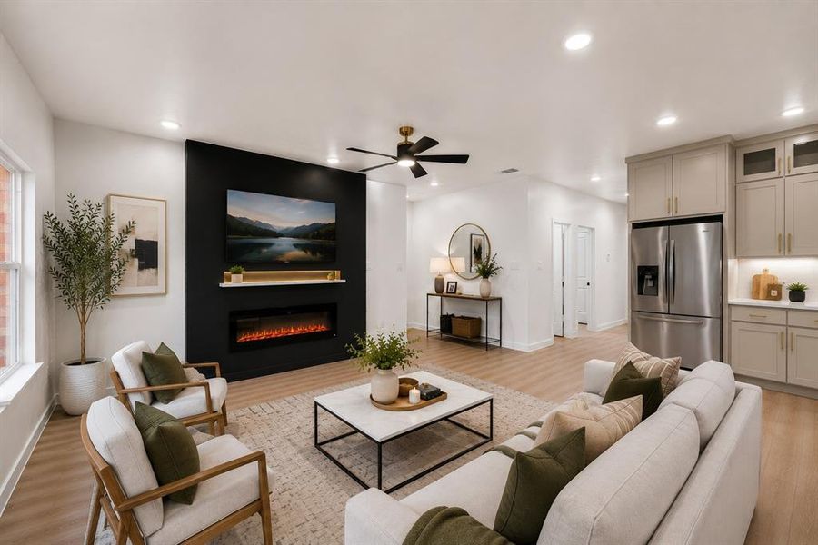 Integrated living space featuring a black accent wall with an electric fireplace, wood-finish flooring, recessed lighting, and a ceiling fan Integrated living space featuring a black accent wall with an electric fireplace, wood-finish flooring, recessed lighting, and a ceiling fan