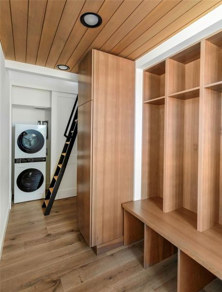 Built-in storage and functional mudroom area with stacked washer and dryer and ladder access to upper loft space.