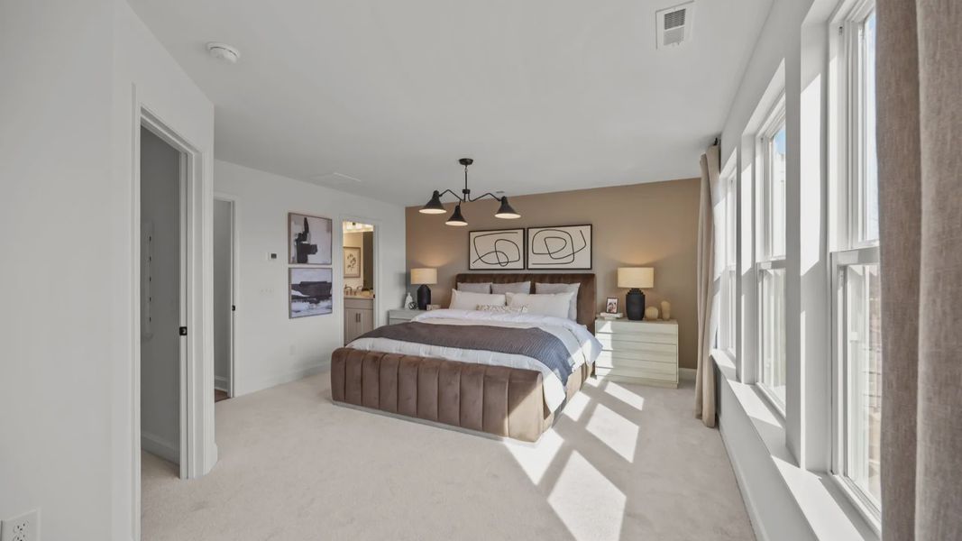The Rochester Plan by DRB homes spacious & cozy primary bedroom with large windows letting in natural light in Charlotte, NC.