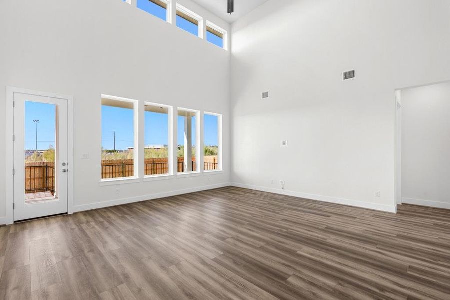 Unfurnished living room with dark wood-style floors and a high ceiling Unfurnished living room with dark wood-style floors and a high ceiling