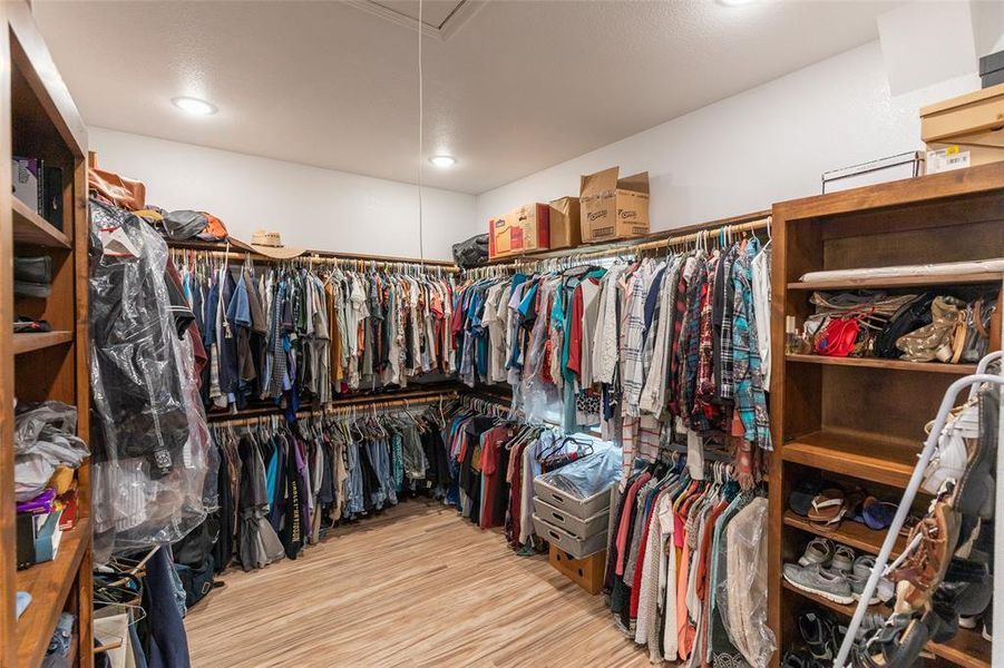 Expansive walk-in closet featuring extensive built-in hanging rods, integrated wood shelving, and wood-finish flooring Expansive walk-in closet featuring extensive built-in hanging rods, integrated wood shelving, and wood-finish flooring