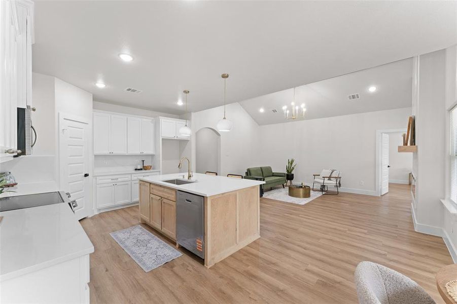 Kitchen with appliances with stainless steel finishes, a sink, open floor plan, light wood finished floors, and light countertops Kitchen with appliances with stainless steel finishes, a sink, open floor plan, light wood finished floors, and light countertops