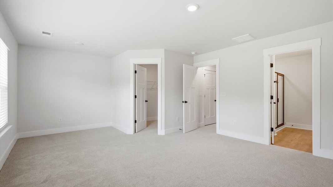 Superior design meets vibrant comfort in this primary suite with carpeted floors and walk-in closet in Greenville, SC Superior design meets vibrant comfort in this primary suite with carpeted floors and walk-in closet in Greenville, SC
