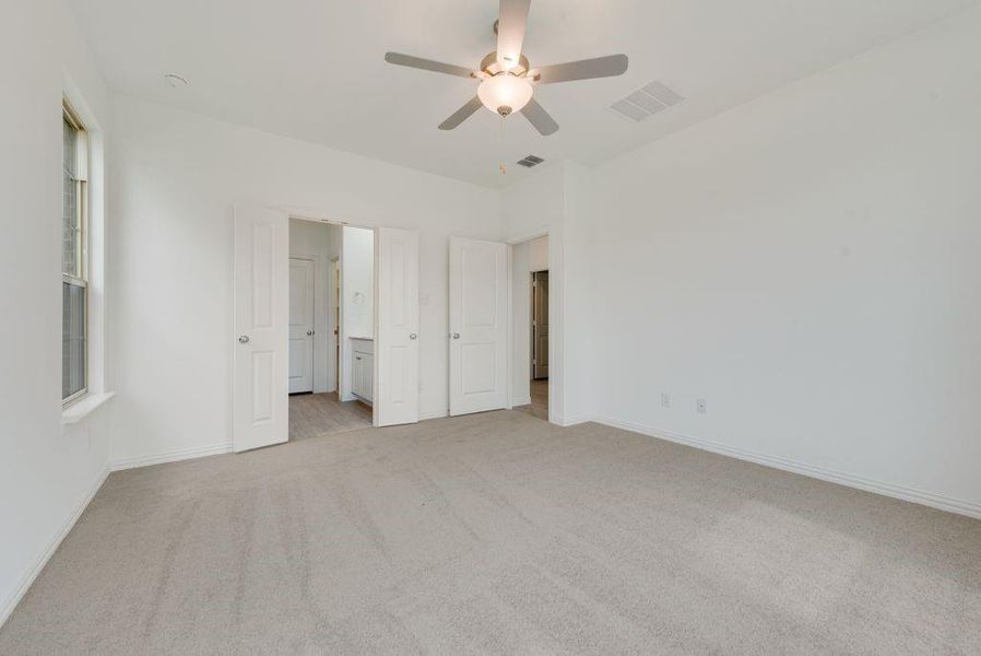 Unfurnished bedroom with light colored carpet, ceiling fan, and ensuite bathroom Unfurnished bedroom with light colored carpet, ceiling fan, and ensuite bathroom