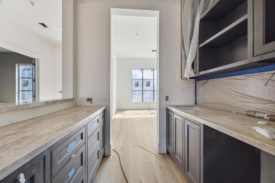 The wet bar and butler's pantry are located between the family and dining rooms. It includes a built-in wine refrigerator, Taj Mahal Quartzite counters, glass front upper cabinets, plenty of storage and herringbone backsplash.