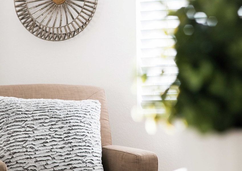 This home is complete with a brown chair with blue patterned pillow, indoor house plant, and decorative multi-spoke round artwork on the wall. This home is complete with a brown chair with blue patterned pillow, indoor house plant, and decorative multi-spoke round artwork on the wall.