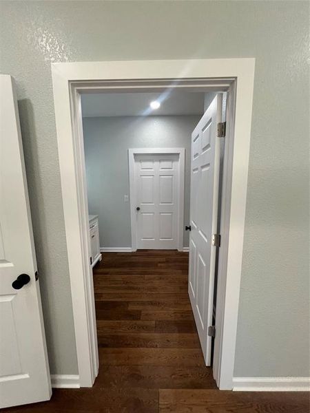 Hallway featuring a textured wall and dark wood finished floors Hallway featuring a textured wall and dark wood finished floors