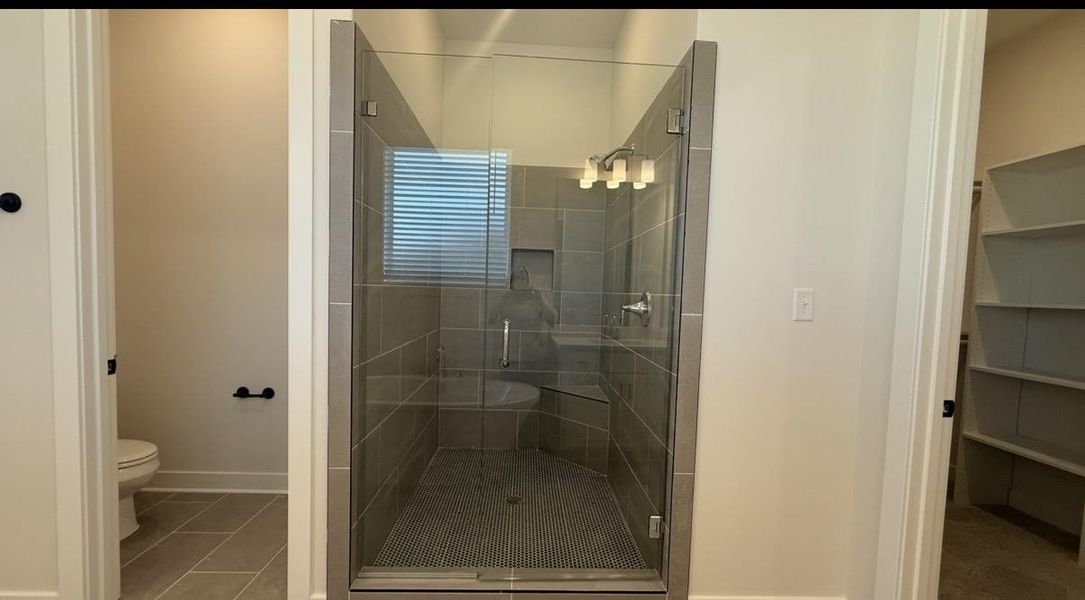 Bathroom featuring a shower stall, light tile patterned floors, and a walk in closet