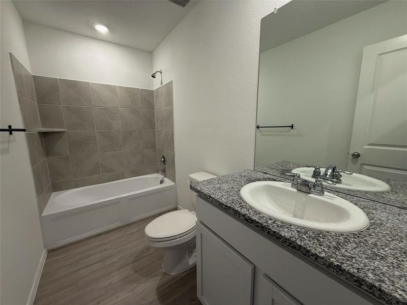 Bathroom featuring a vanity with a granular countertop, an undermount sink, and a large wall mirror Bathroom featuring a vanity with a granular countertop, an undermount sink, and a large wall mirror