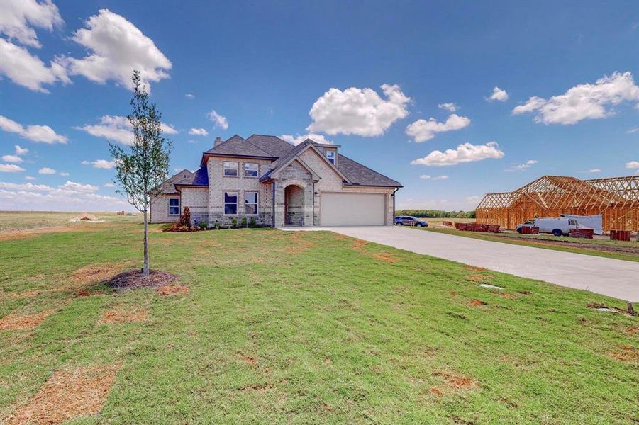 French country inspired facade with a garage and a front lawn