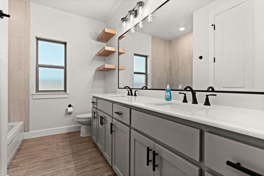 Bathroom featuring plenty of natural light, double vanity, wood finish floors, and tub / shower combination Bathroom featuring plenty of natural light, double vanity, wood finish floors, and tub / shower combination