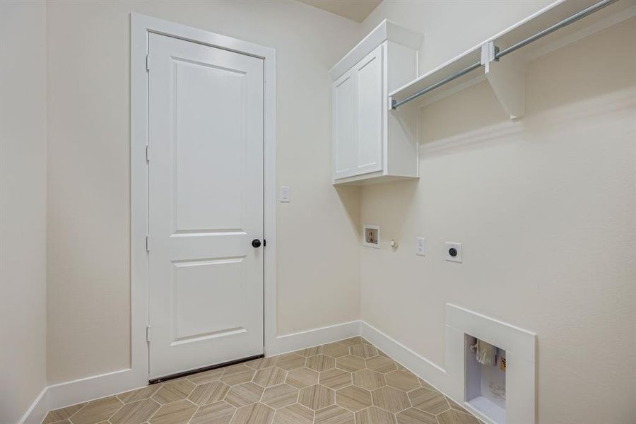 Washroom featuring hookup for a gas dryer, washer hookup, electric dryer hookup, cabinet space, and light tile patterned floors Washroom featuring hookup for a gas dryer, washer hookup, electric dryer hookup, cabinet space, and light tile patterned floors