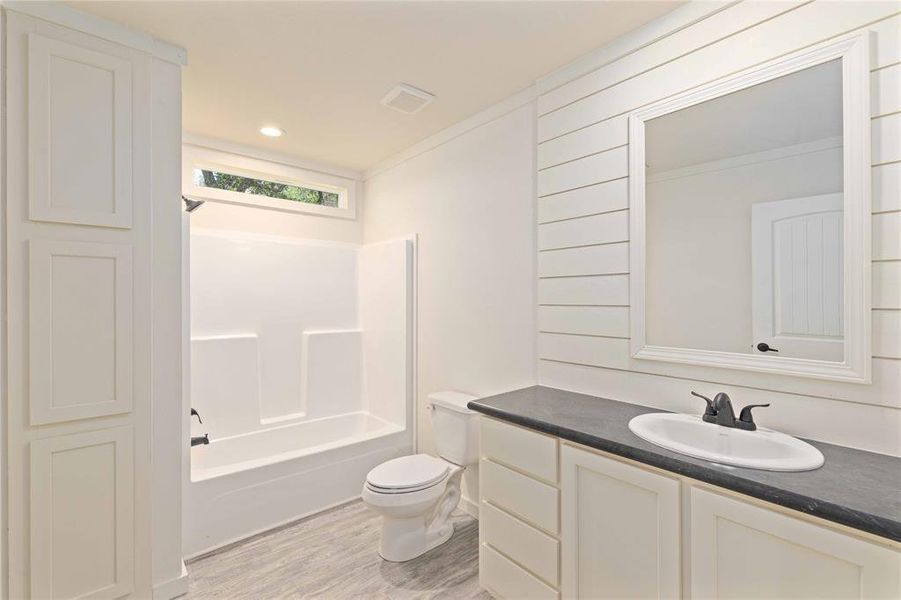 Bathroom featuring a single vanity with a dark countertop, white undermount sink, and black faucet