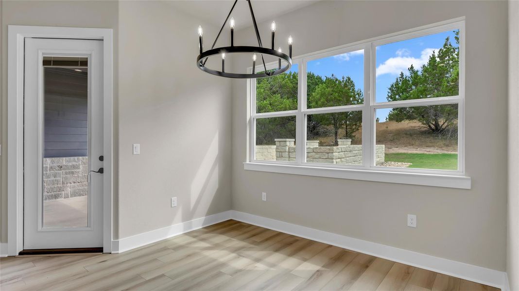 Unfurnished dining area featuring suspended lighting and light wood-type flooring