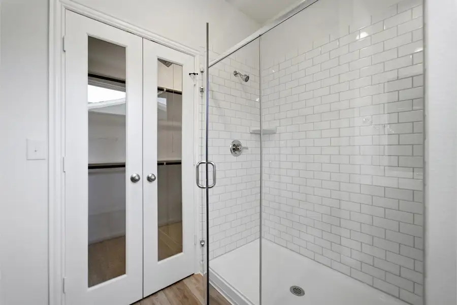 Bathroom with a shower stall, light wood-style flooring, and french doors Bathroom with a shower stall, light wood-style flooring, and french doors