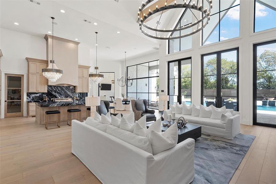 Living area featuring a chandelier, a high ceiling, recessed lighting, plenty of natural light, and light wood-type flooring