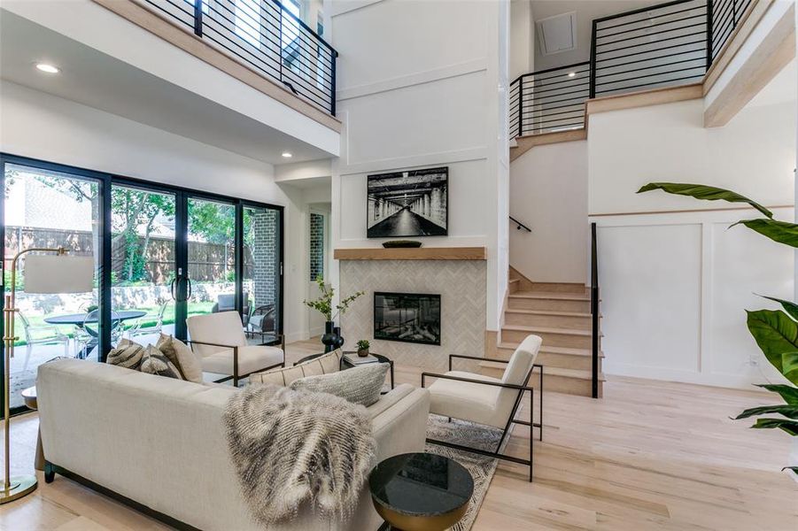 Living room featuring a high ceiling, light hardwood / wood-style floors, a fireplace, and french doors