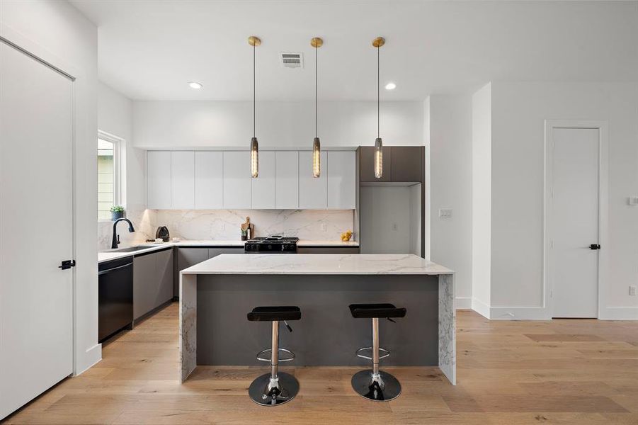 This elegant kitchen features sophisticated European-style cabinets with sleek, minimalist lines paired with stunning quartz countertops for a modern luxury and timeless appeal.