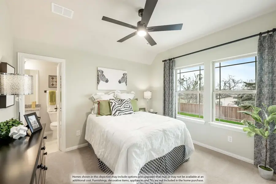 Bedroom with ceiling fan, ensuite bathroom, vaulted ceiling, and two windows with patterned curtains