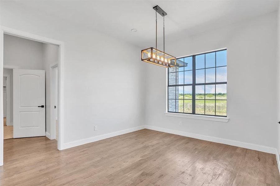 Empty room with light hardwood / wood-style floors and a chandelier