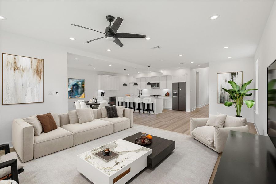 Spacious open-concept view from the living room, highlighting the seamless flow into the kitchen and dining area. Features include a ceiling fan, durable vinyl plank flooring, high ceilings, and large windows that bring in plenty of natural light. *Photo is virtually staged*