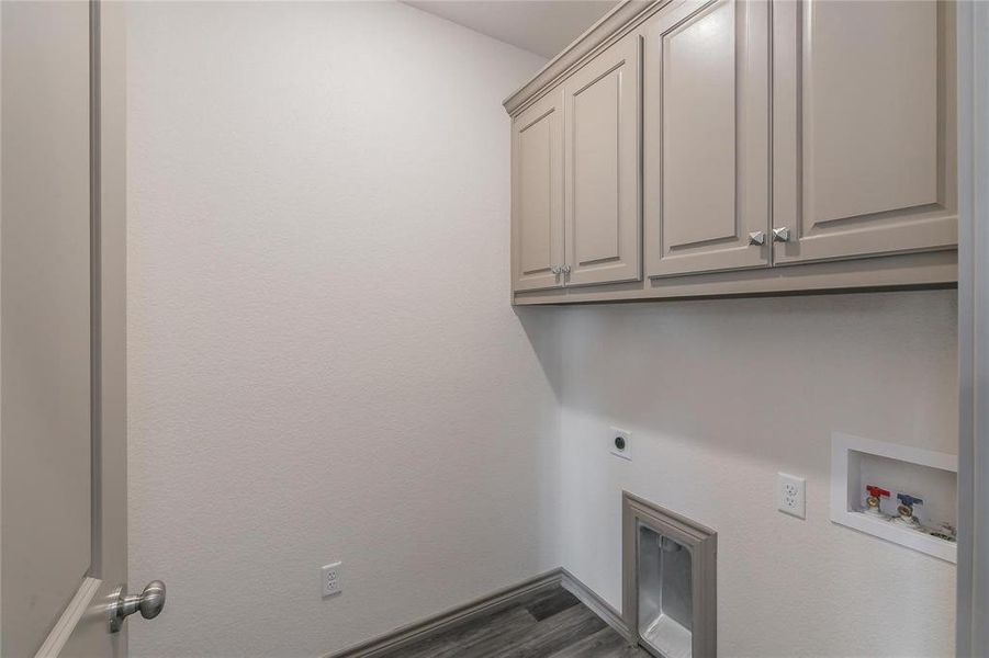 Laundry area with dark wood-type flooring, cabinet space, hookup for an electric dryer, and washer hookup