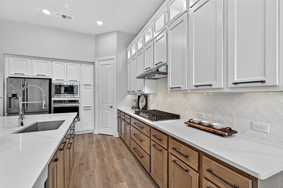 Kitchen featuring stainless steel appliances, under cabinet range hood, decorative backsplash, white cabinets, and recessed lighting Kitchen featuring stainless steel appliances, under cabinet range hood, decorative backsplash, white cabinets, and recessed lighting