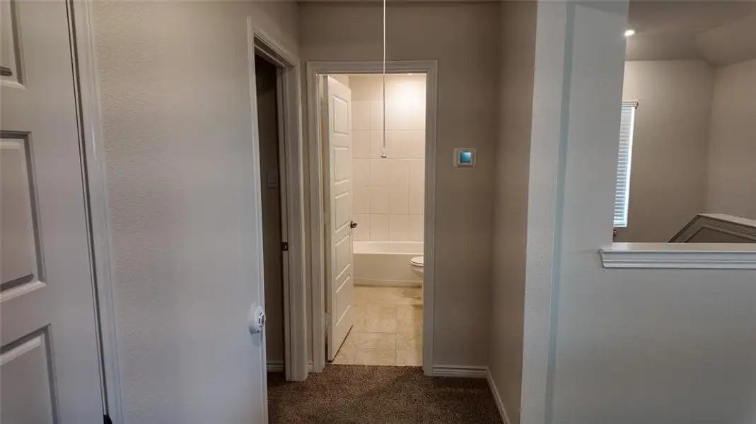 Hall with dark carpet and dark tile patterned flooring