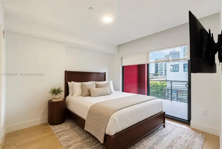 Bedroom featuring wood-finish flooring, recessed lighting, and a sliding glass door providing access to a private balcony Bedroom featuring wood-finish flooring, recessed lighting, and a sliding glass door providing access to a private balcony