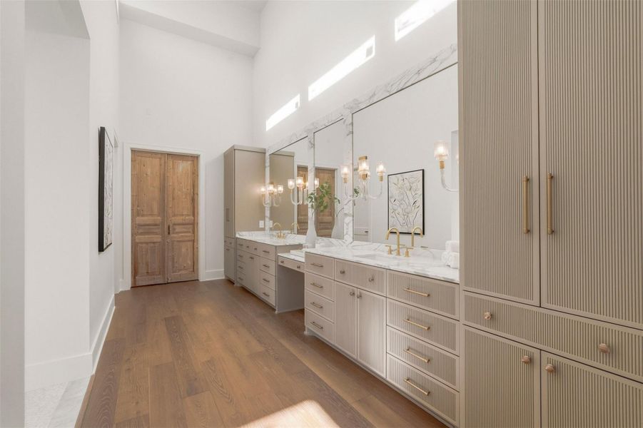 Just inside the double French doors, a luxurious bath suite reminiscent of a five-star resort, featuring soaring ceilings, dual vanities with marble countertops, wall sconces, and fluted cabinets. Just inside the double French doors, a luxurious bath suite reminiscent of a five-star resort, featuring soaring ceilings, dual vanities with marble countertops, wall sconces, and fluted cabinets.