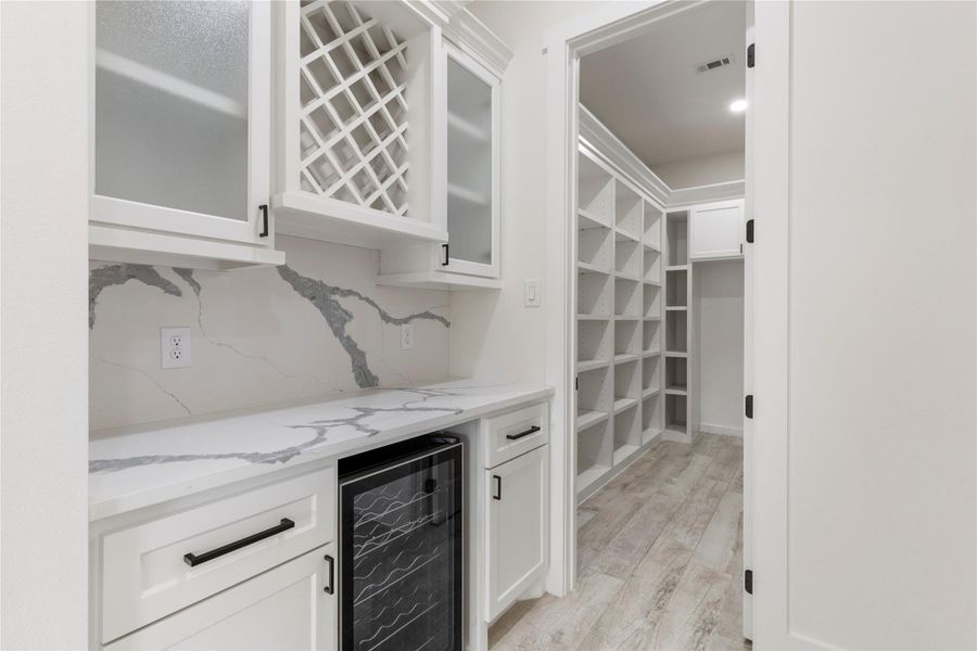 Butler's pantry also includes the beautiful quartz countertops, wine fridge, and black hardware for continuity. Butler's pantry also includes the beautiful quartz countertops, wine fridge, and black hardware for continuity.