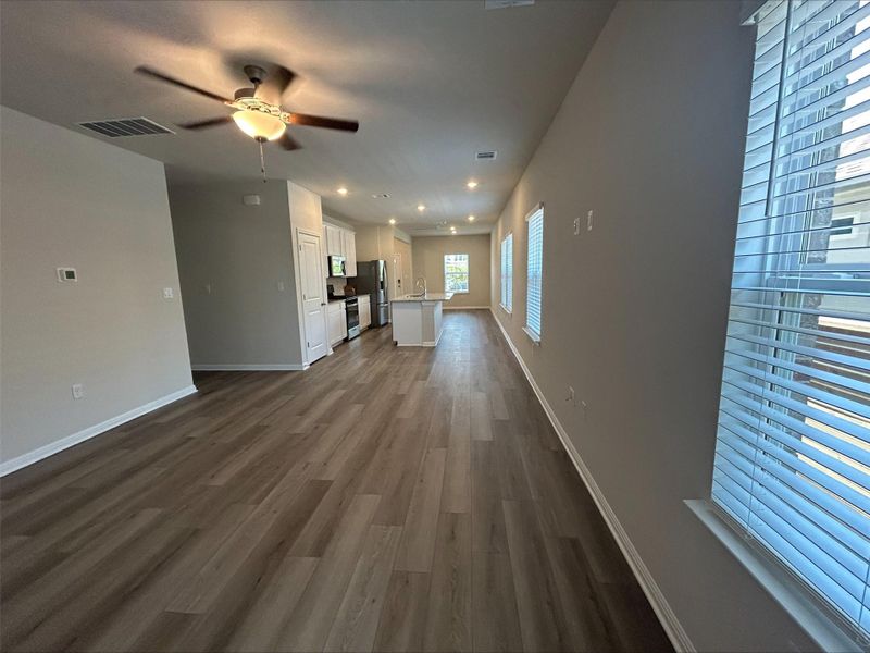Unfurnished living room with ceiling fan and dark wood-style flooring Unfurnished living room with ceiling fan and dark wood-style flooring