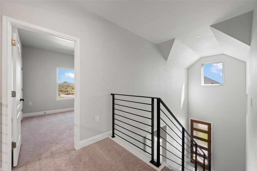 Hallway featuring an upstairs landing, plenty of natural light, light colored carpet, vaulted ceiling, and recessed lighting