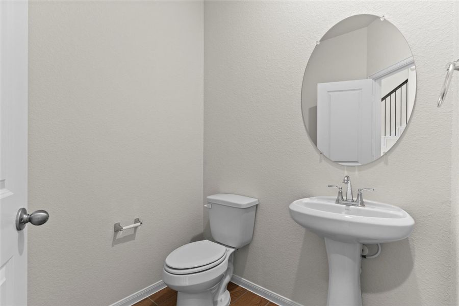 Convenient first floor half bath featuring a pedestal sink, classic fixtures, and a clean bright design for guests. This powder room is ideally located on the main level for easy access from the living areas.
