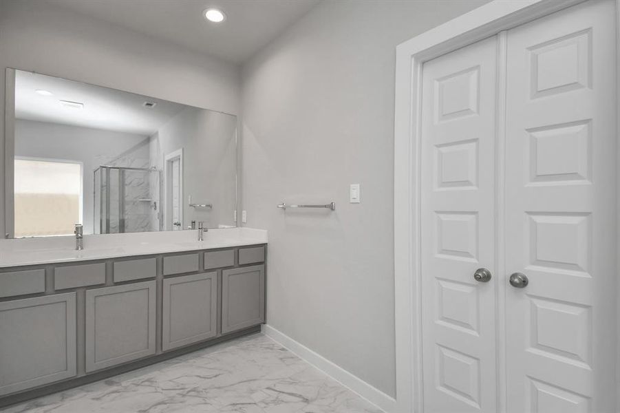 This beautiful bathroom is located alongside a spacious walk-in closet with shelving, high ceilings, custom paint, and sleek, dark modern finishes. An ideal retreat for unwinding after a long day.