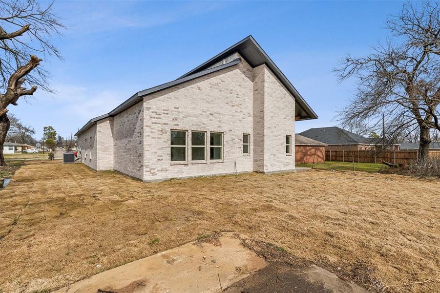 Back of property featuring central air condition unit and a lawn