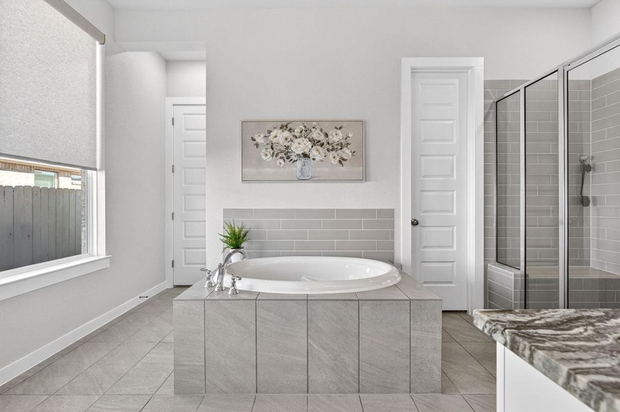 Primary bathroom featuring a beautiful walk-in shower, a large bath, and tile  flooring