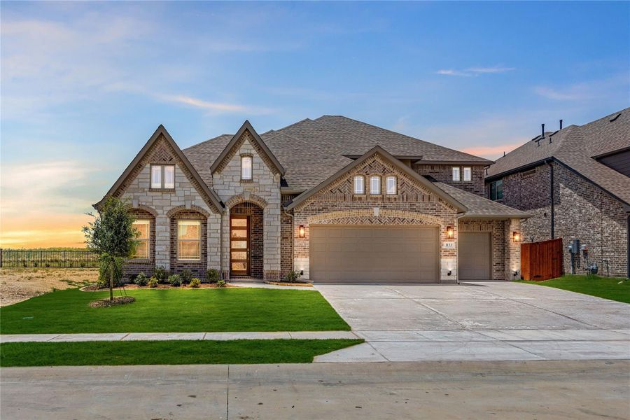 Single-story brick and stone home with three-car garage, arched entry, and manicured front lawn at dusk. Single-story brick and stone home with three-car garage, arched entry, and manicured front lawn at dusk.