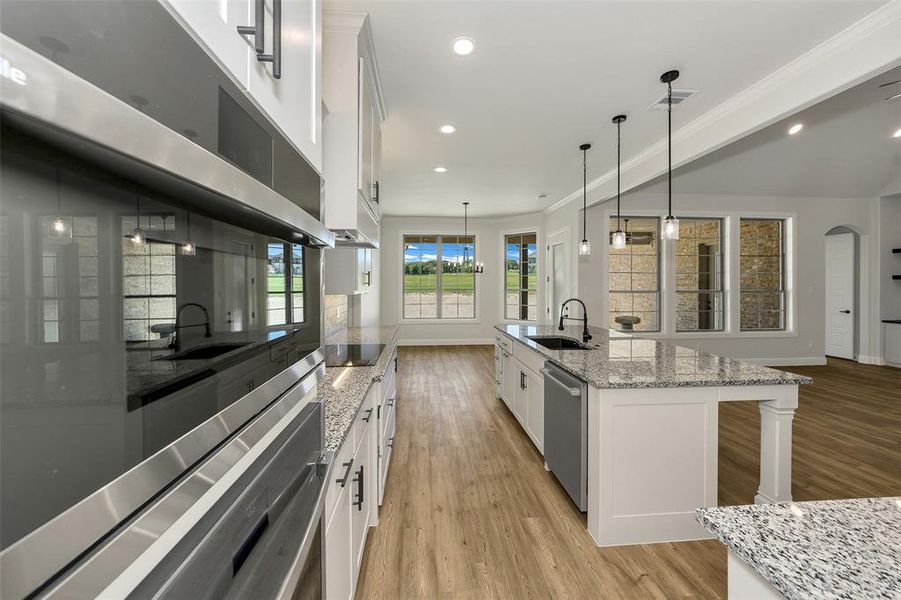 Kitchen with light wood-style flooring, white cabinets, recessed lighting, ornamental molding, and pendant lighting