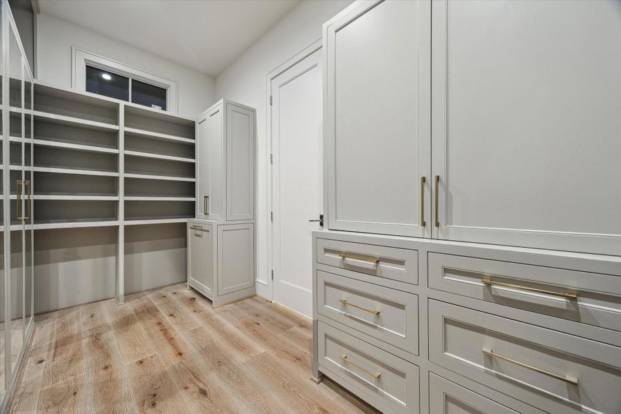 The primary closet. Wardrobe boxes with custom-fabricated doors exude a fashion house feel. Soft-close hinges are another element of quiet luxury. Accessory shelves are thoughtfully placed for purses, shoes, and more!