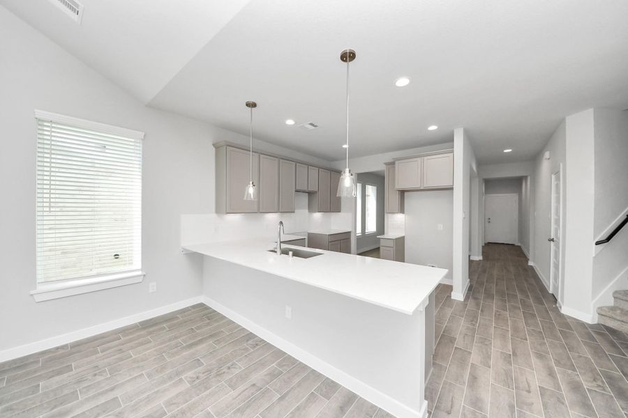 Culinary haven, featuring granite countertops, a tile backsplash, stainless steel appliances, 42” upper cabinets, and undercabinet lighting. Sample photo of completed home with similar floor plan. Actual colors and selections may vary. Culinary haven, featuring granite countertops, a tile backsplash, stainless steel appliances, 42” upper cabinets, and undercabinet lighting. Sample photo of completed home with similar floor plan. Actual colors and selections may vary.