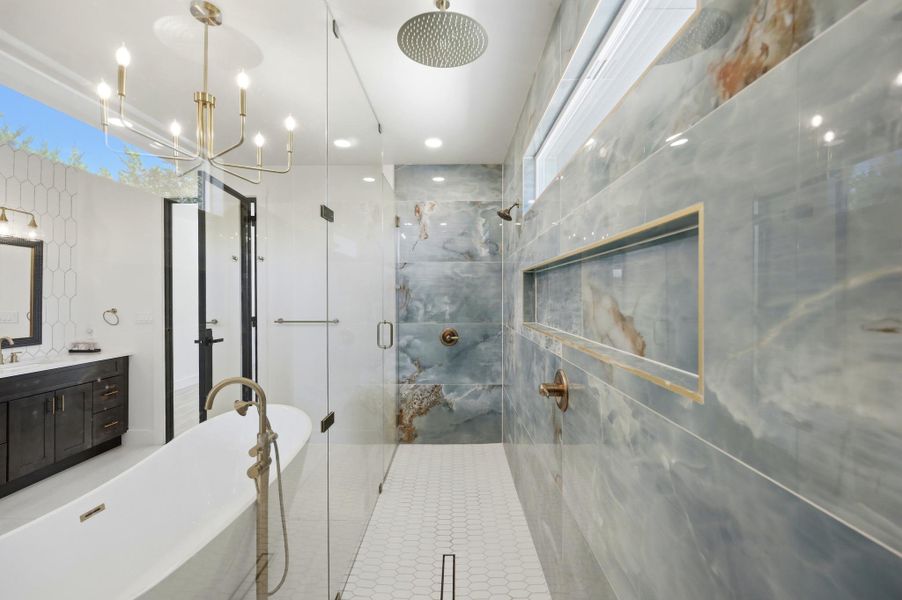 Exquisite stone tiling and a sleek freestanding tub define this luxurious modern bath space.