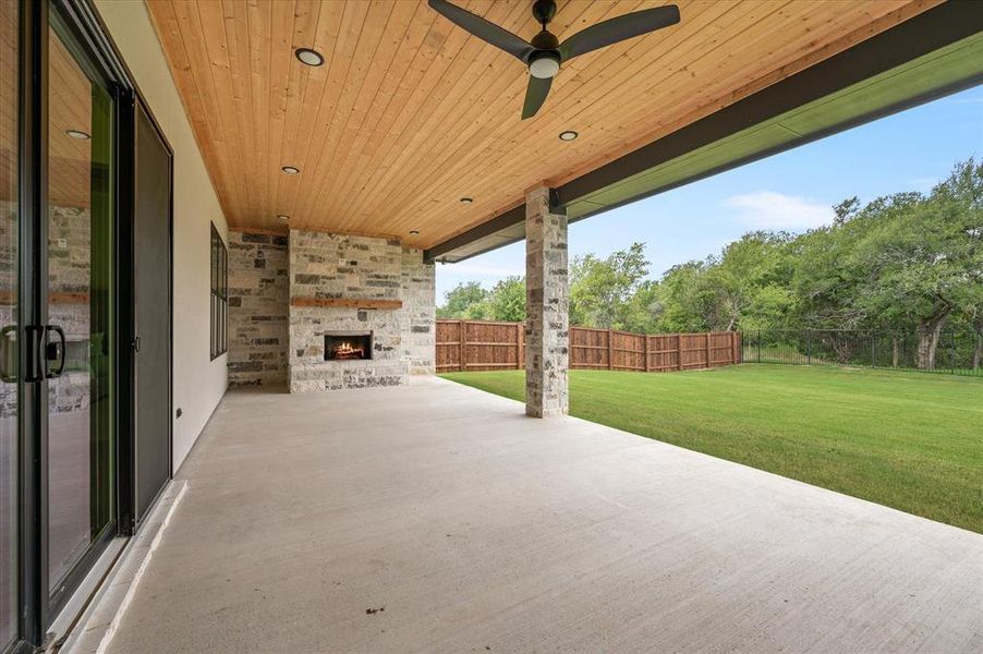 View of patio featuring an outdoor stone fireplace and ceiling fan