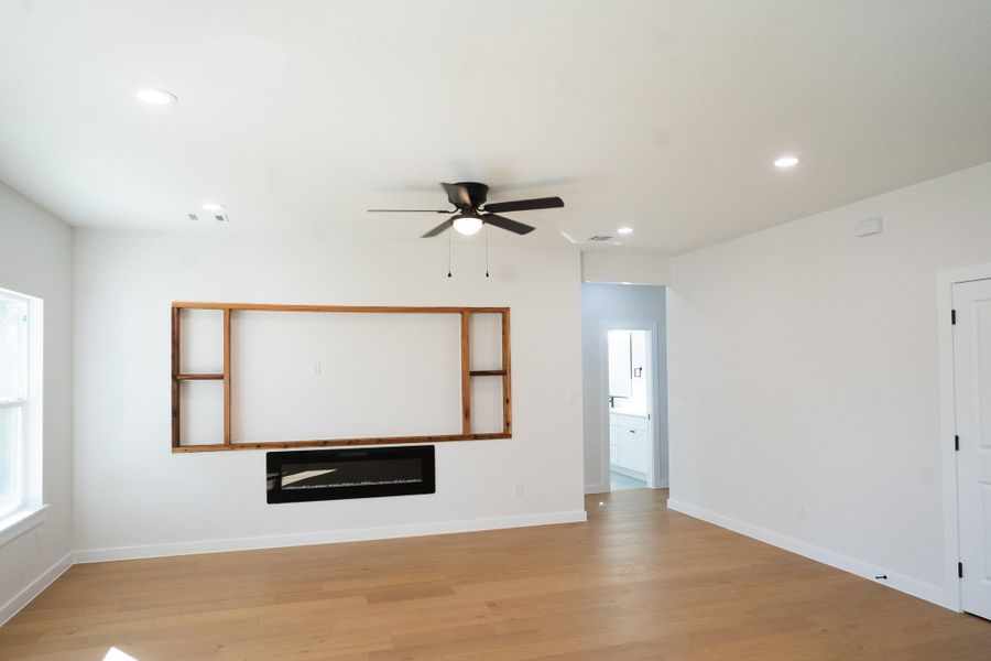 Unfurnished living room featuring ceiling fan, wood finished floors, recessed lighting, and a glass covered fireplace