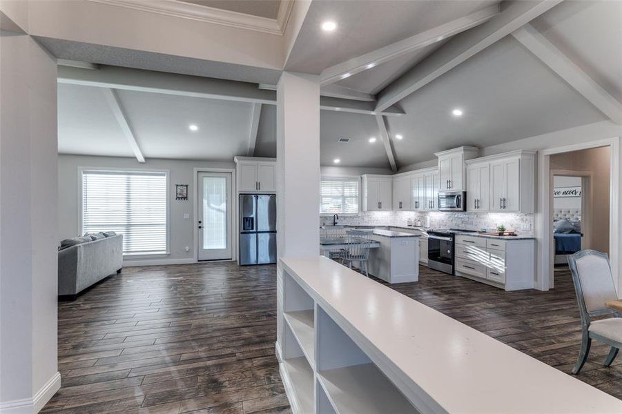 Kitchen with a center island, stainless steel appliances, decorative backsplash, white cabinets, and open floor plan
