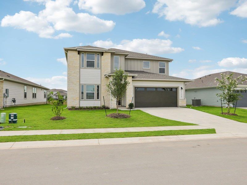 View of front of property with concrete driveway, stone siding, a front lawn, central AC, and board and batten siding View of front of property with concrete driveway, stone siding, a front lawn, central AC, and board and batten siding