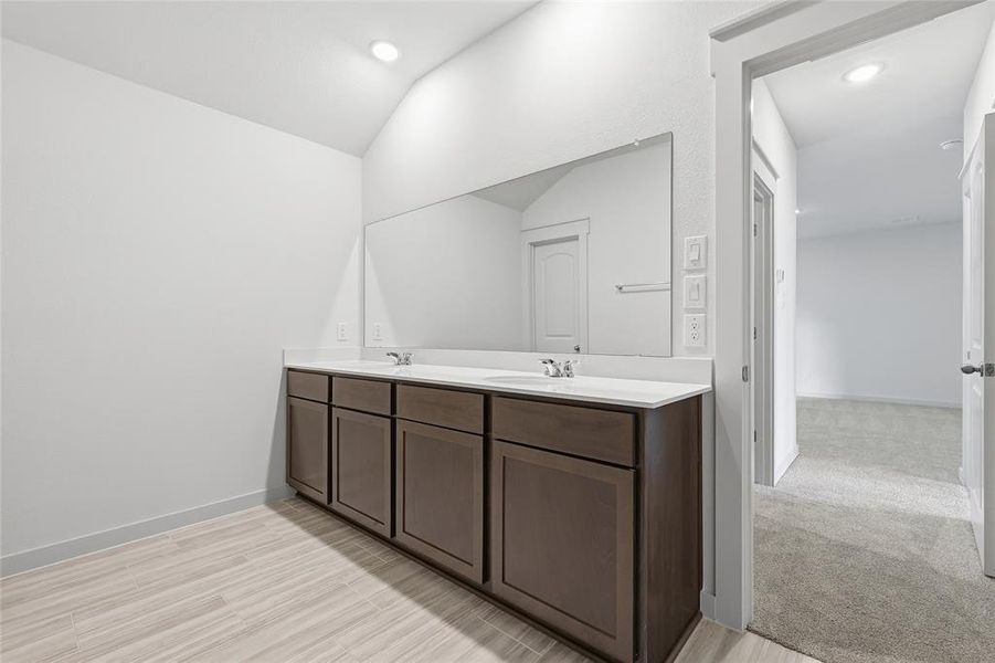 Bathroom featuring double vanity, recessed lighting, vaulted ceiling, and light wood-style floors Bathroom featuring double vanity, recessed lighting, vaulted ceiling, and light wood-style floors